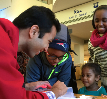 MIT grad student Sumit Dutta tests out a prototype of his computer logic activity with visitors during a science communication internship at MOS, part of a DOE research center–Museum partnership.