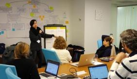 Person presenting at a meeting to a table of other people